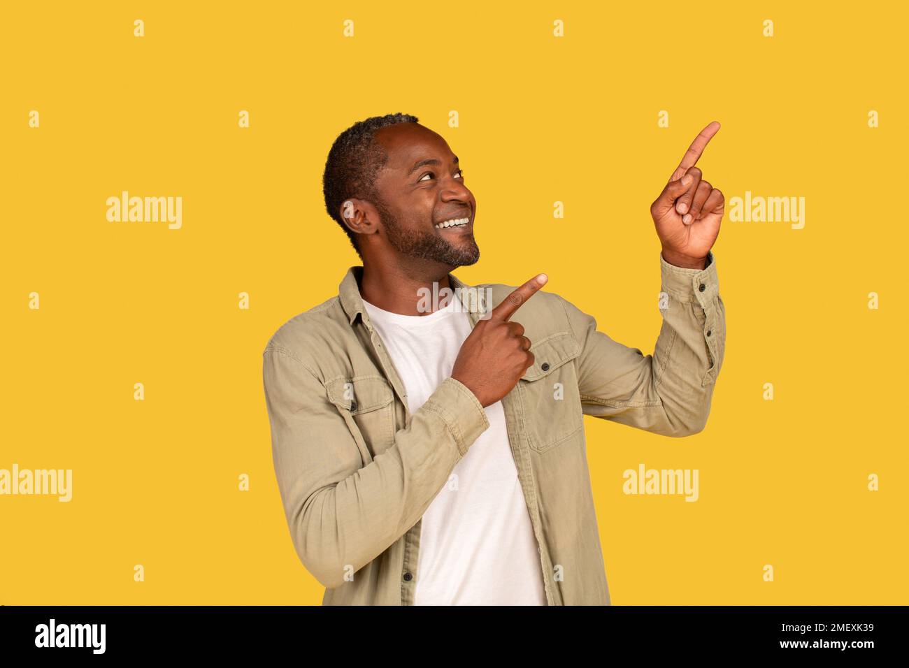 Empfehlungen, Ratschläge und Blick hier. Ein glücklicher afroamerikanischer Mann mittleren Alters, der mit dem Finger auf den leeren Raum zeigt Stockfoto