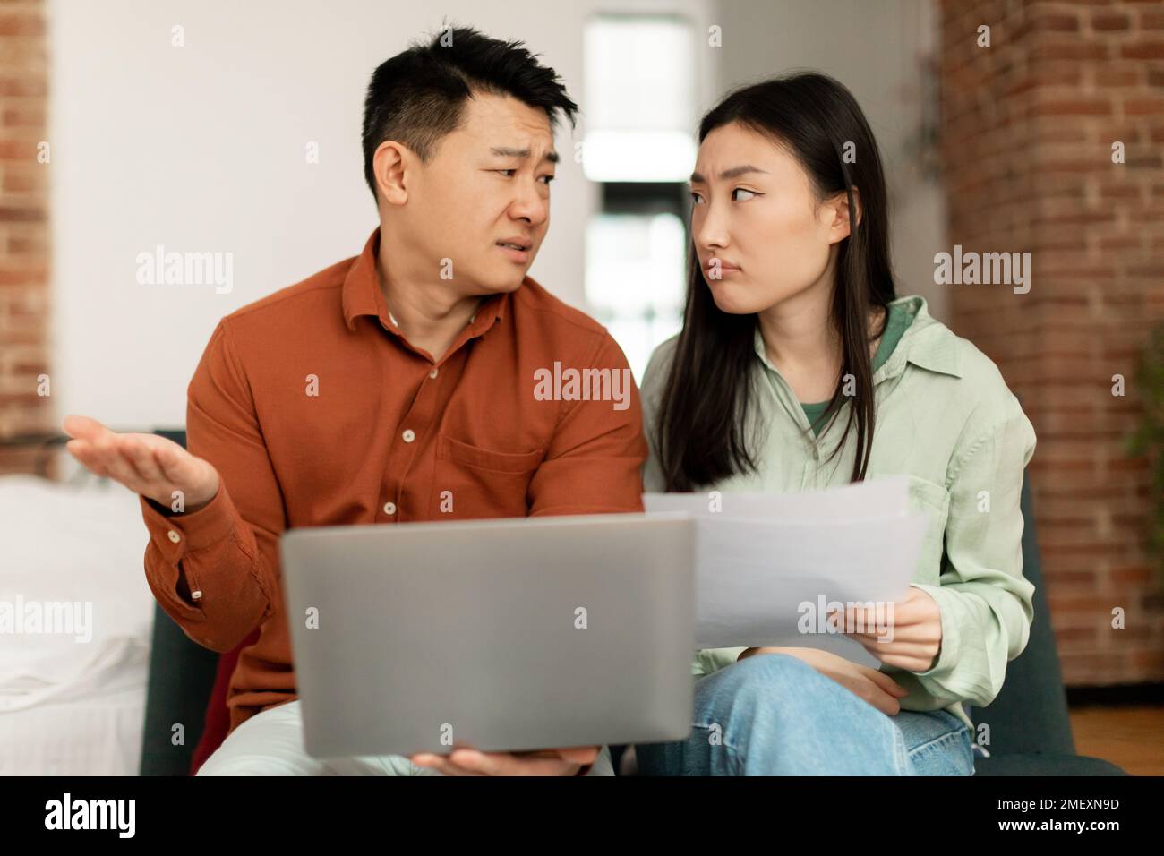 Finanzkrisenkonzept. Aufgewühltes asiatisches Paar, das zu Hause Dokumente überprüft, leidet unter Problemen mit der Verwaltung des Familienbudgets Stockfoto