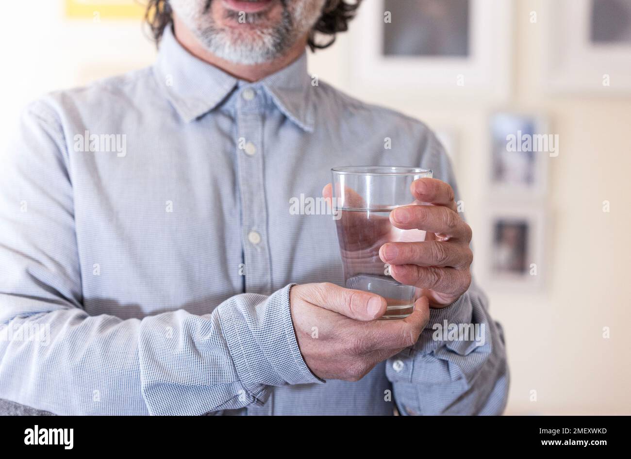 Ein lächelnder Mann, der zu Hause ein Glas Wasser hält. Konzept gesundes Leben Stockfoto