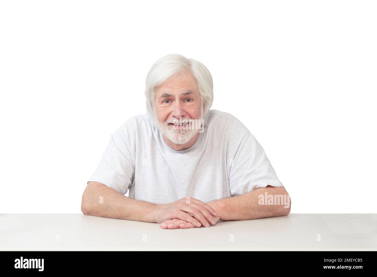 Horizontale Aufnahme eines fröhlichen, weißhaarigen Mannes, der auf einem Tisch auf weißem Hintergrund führt. Viel Platz zum Kopieren. Stockfoto