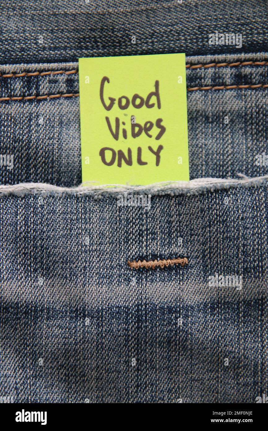Gutes Vibes-Only-Konzept Motivationszettel auf einem Anhänger in einer Tasche mit blauen Jeans. Stockfoto