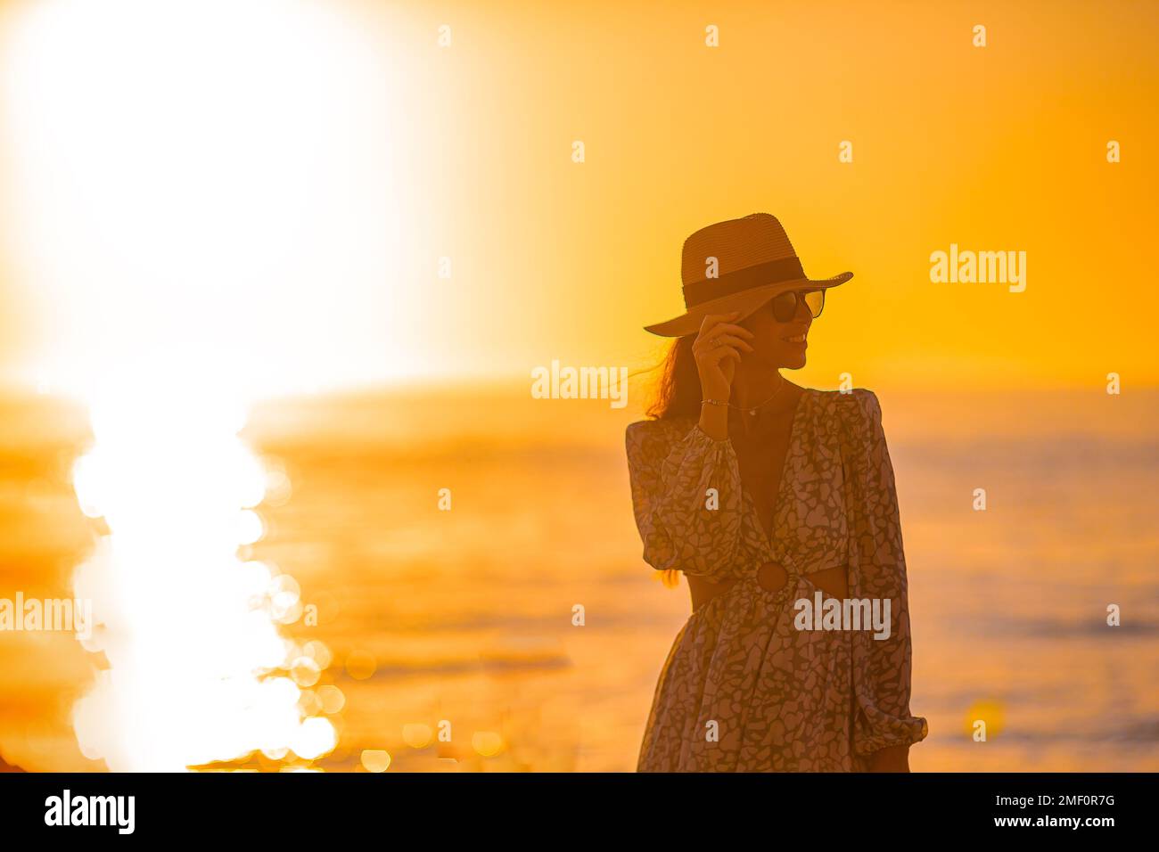 Junge glückliche Frau am Strand genießt ihren Sommerurlaub bei Sonnenuntergang Stockfoto