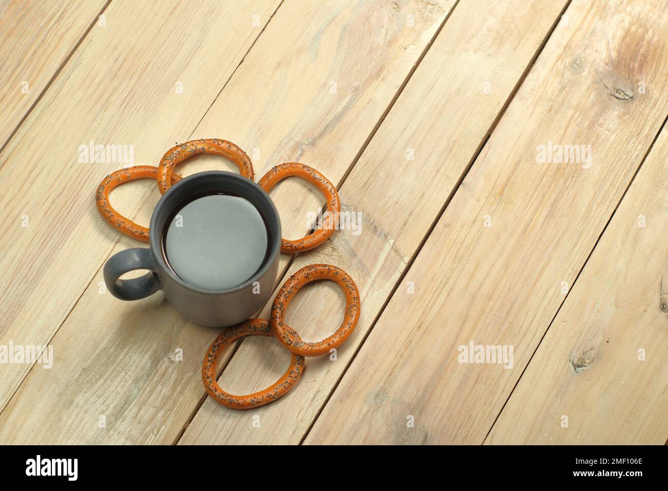 Eine Tasse mit Kaffee neben einem Bagel auf einem Plankentisch Stockfoto