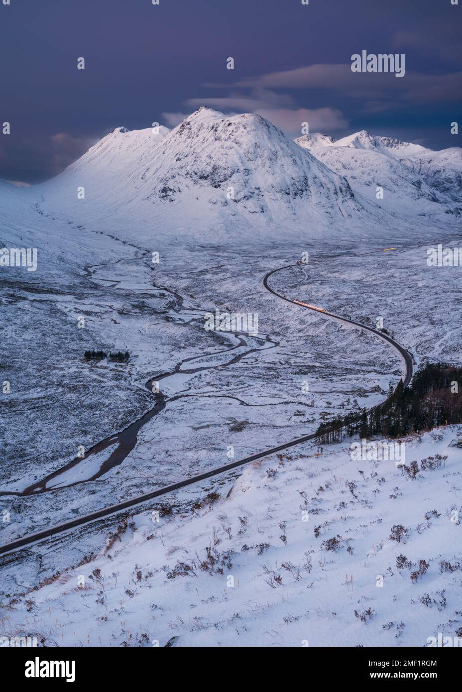 Lange kurvenreiche Straße durch das schneebedeckte Tal von Glencoe, Großbritannien. Stockfoto