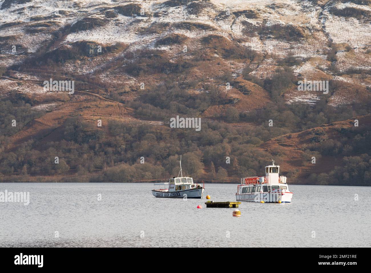 Zwei Loch Lomond Cruiser Boote auf dem See mit schneebedeckten Bergen im Hintergrund. Stockfoto