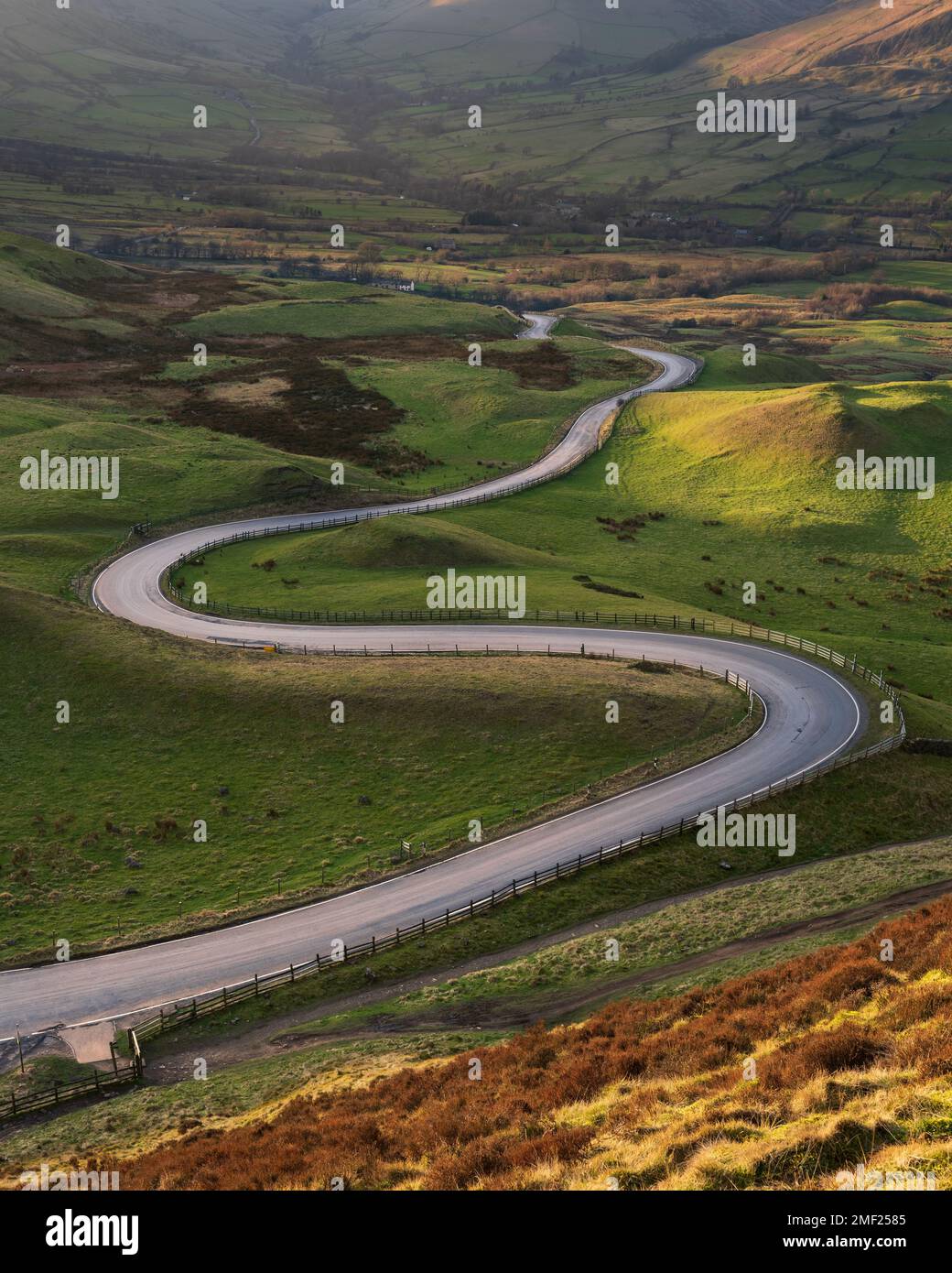 Lange kurvenreiche Straße, die durch das britische Tal unter dem Mam Tor im Peak District führt. Konzeptionelle Landschaftshintergründe. Stockfoto