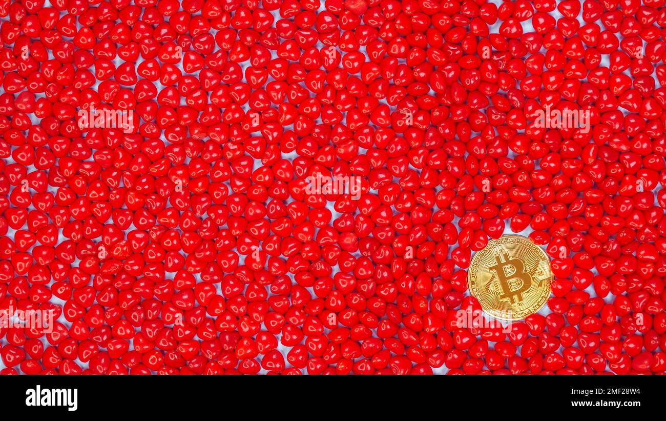 Goldene Bitcoin-Münze auf einem roten herzförmigen Bonbon-Hintergrund. Bitcoin Kryptowährung Wert Preis fallen, nach unten, rote Aktienkarte. Krypto-Währung süß Stockfoto