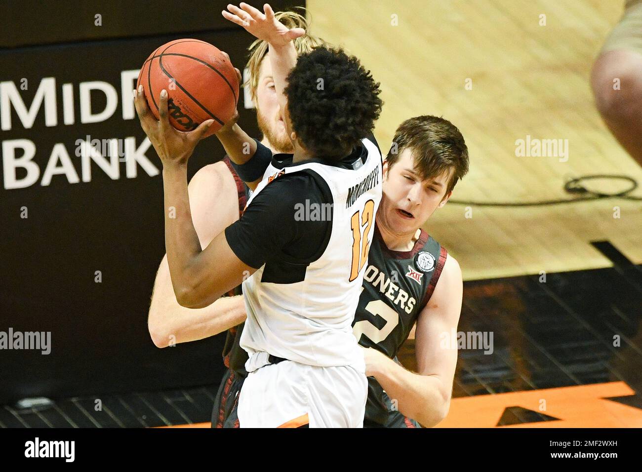 Oklahoma guard Austin Reaves (12) fouls Oklahoma State forward Matthew-Alexander Moncrieffe (12) under the basket during the second half of an NCAA college basketball game Monday, March 1, 2021, in Stillwater, Okla. (AP Photo/Brody Schmidt) Stockfoto