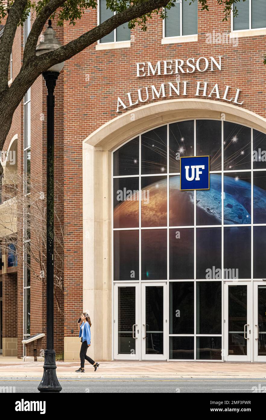 Eine Studentin, die mit einem Handy spricht, während sie die Emerson Alumni Hall auf dem Campus der University of Florida in Gainesville, Florida passiert. (USA) Stockfoto