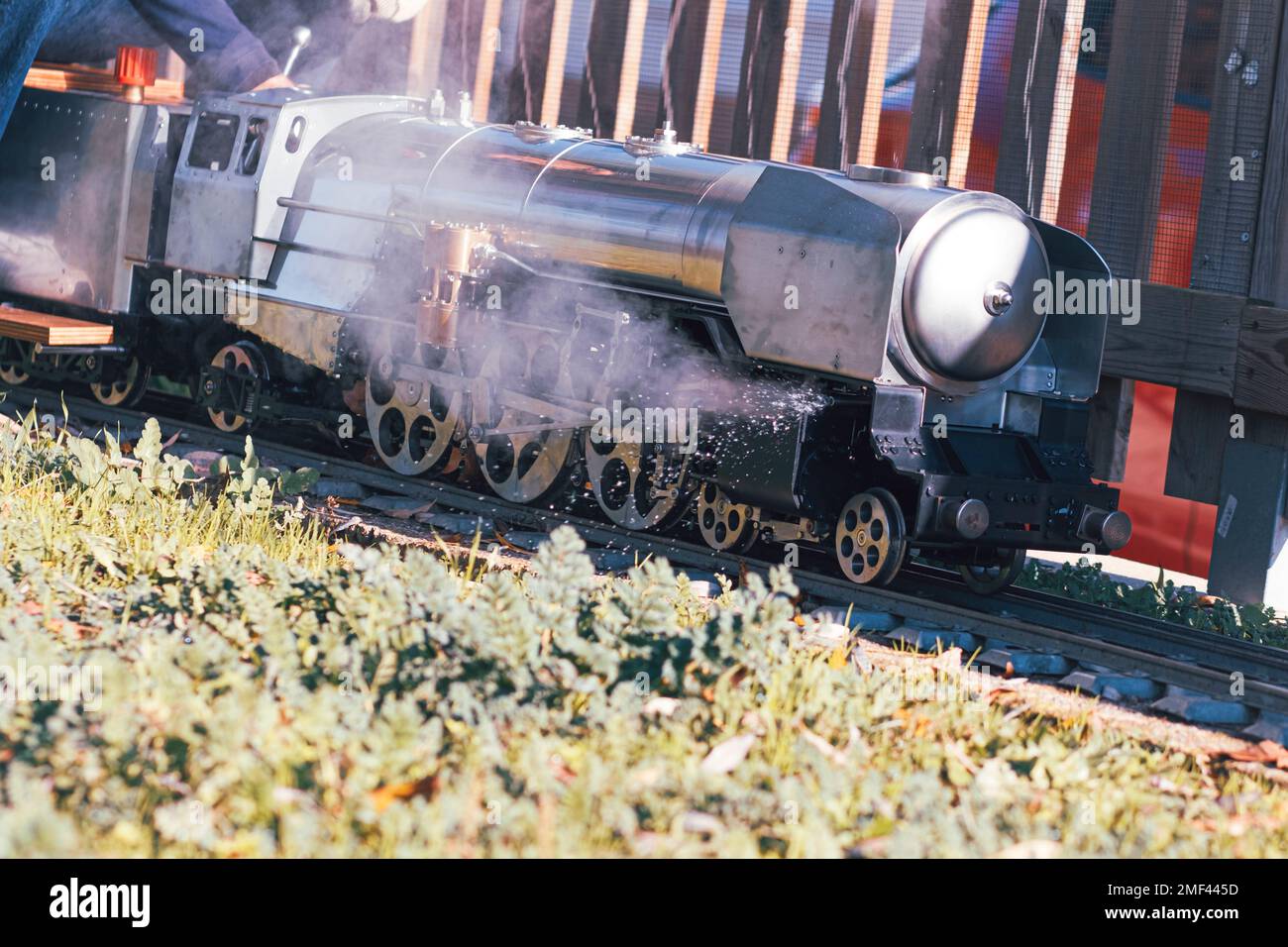 Winzige Dampfbahn aus Metall, die schnell auf einem Bahnhof fährt Stockfoto