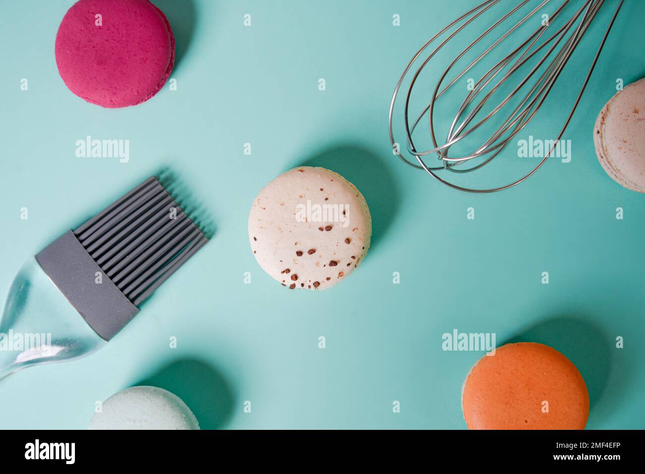 Bunte Makronen. Kleine französische Kuchen. Kochen, Schneebesen, gebrochene Makronen, Früchte, Erdbeeren, Himbeeren und Brombeeren. Kochen auf blauem Boden Stockfoto