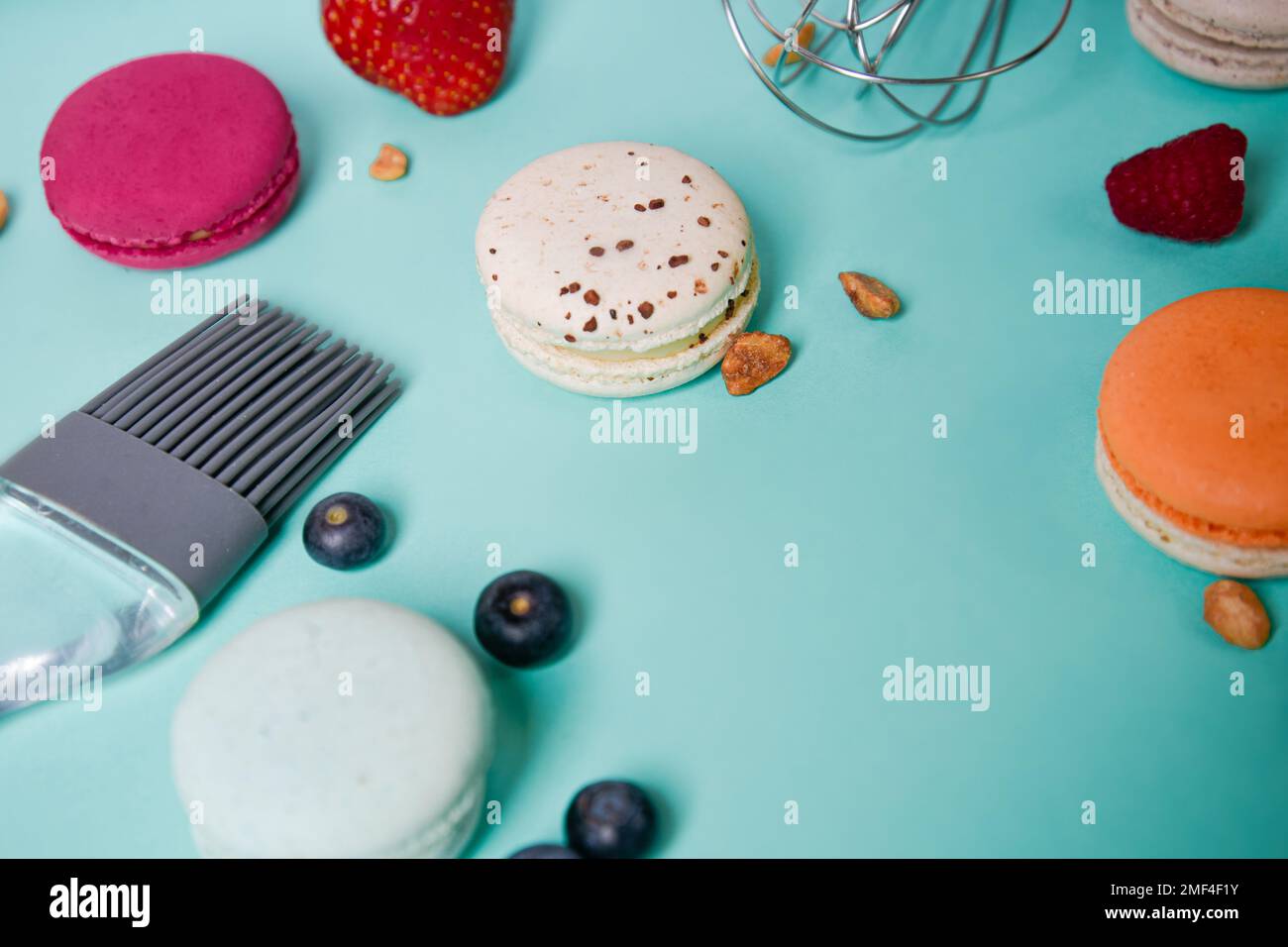 Bunte Makronen. Kleine französische Kuchen. Kochen, Schneebesen, gebrochene Makronen, Früchte, Erdbeeren, Himbeeren und Brombeeren. Kochen auf blauem Boden Stockfoto