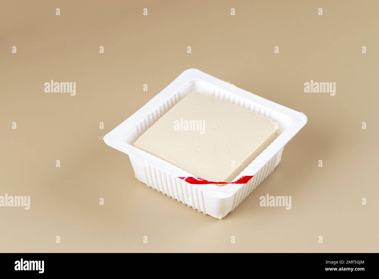 Seidenglatte Tofu oder Tahu Sutra auf Supermarkt-Plastikverpackungen. Isoliert auf cremefarbenem Hintergrund Stockfoto