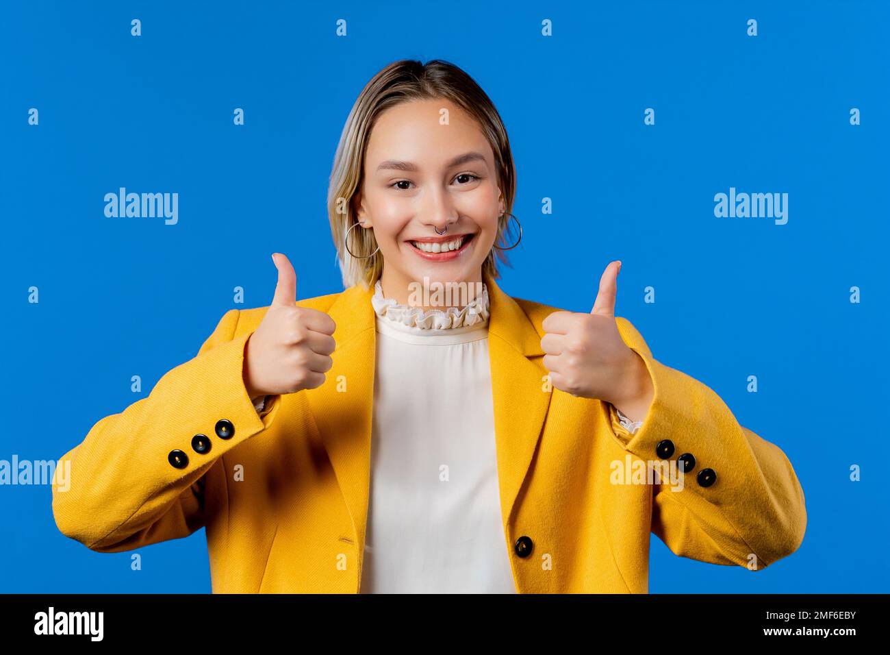 Stilvolle Frau mit Handzeichen, Daumen-hoch-Geste. Lady auf blauem Hintergrund Stockfoto