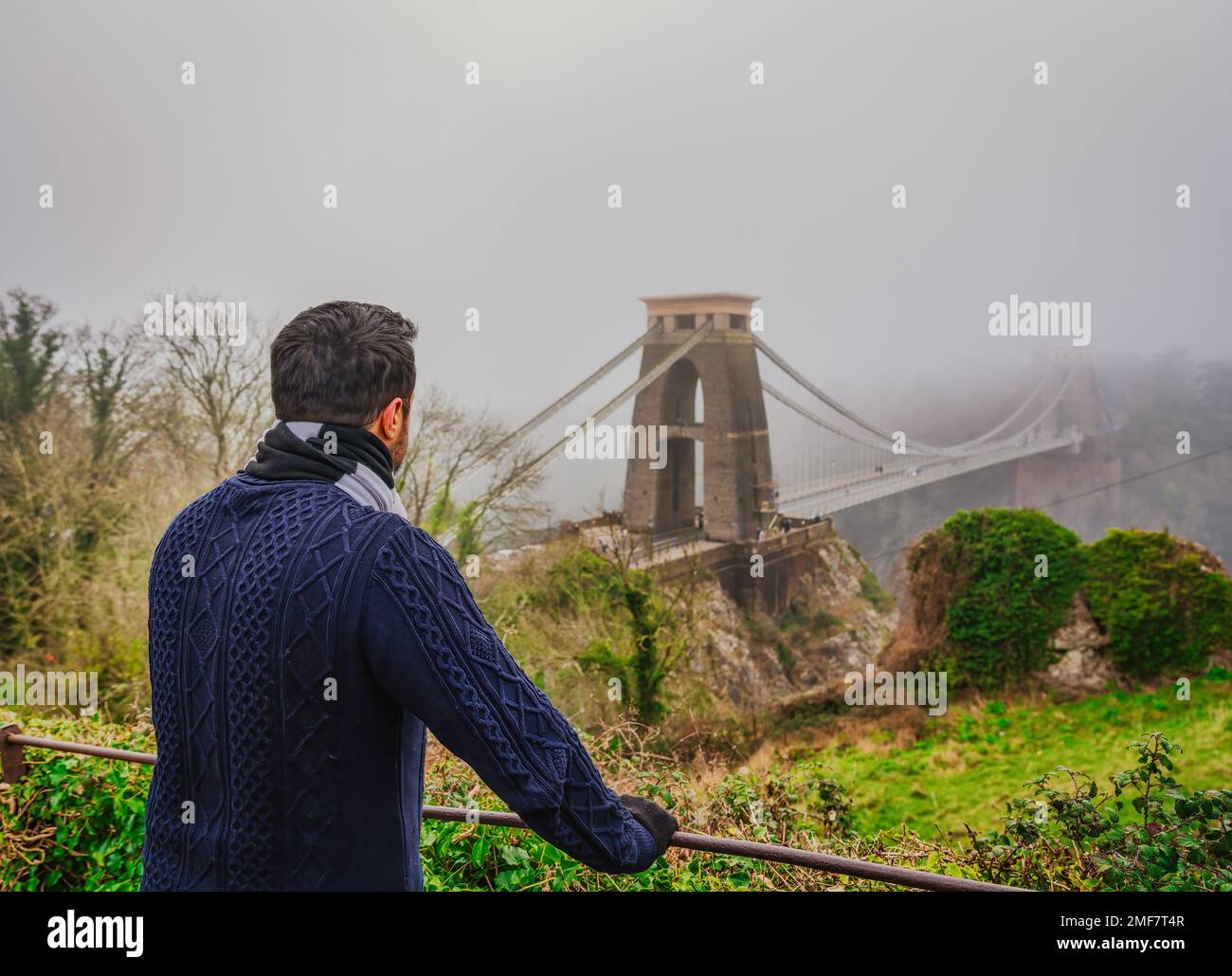 Ein Mann, der an einem nebligen Tag auf die berühmte Clifton Bridge in Bristol England schaut Stockfoto