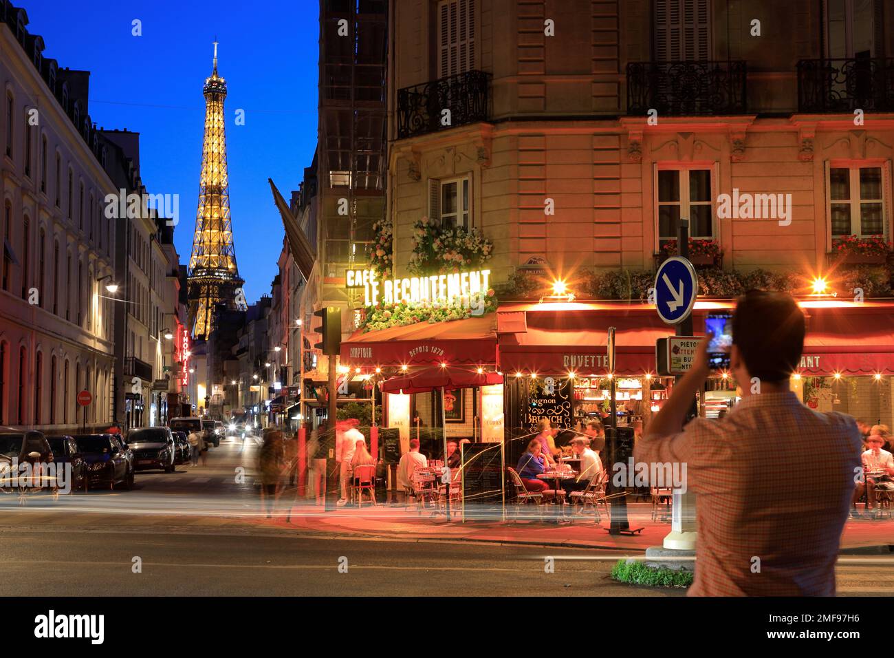 Nachtsicht auf den Eiffelturm und das Café Le Recrutement an der Ecke Rue Saint-Dominique und Boulevard de la Tour-Maubourg mit Rücklichtpfaden. Paris. Frankreich Stockfoto