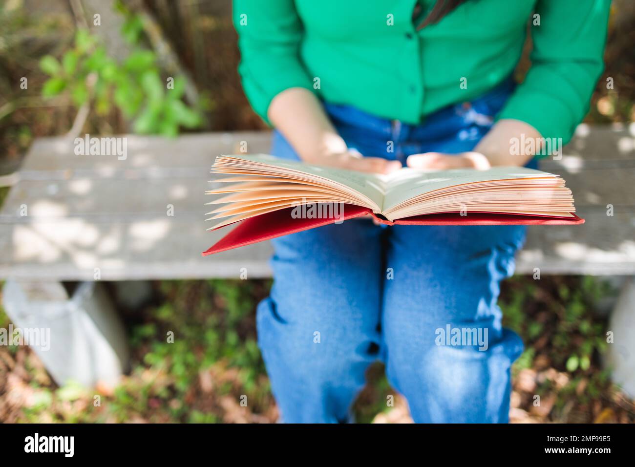 Eine nicht wiedererkennbare Studentin, die im Garten ein Buch liest. Weltbuchtag. Vorteile des Lesens Stockfoto