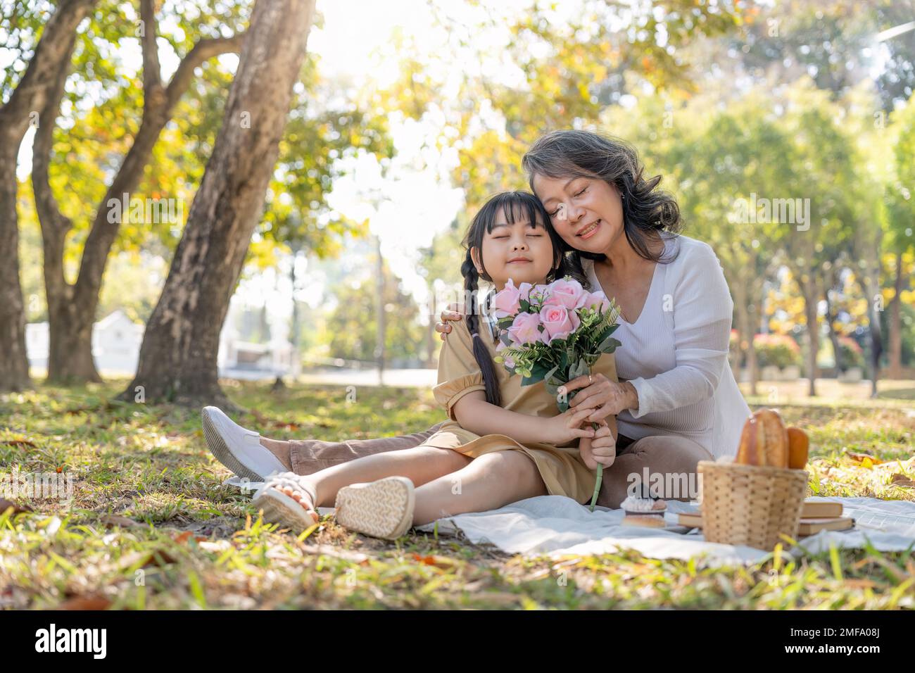 Glückliche asiatische Großmutter, die sich mit ihrer liebenswerten Enkelin im Park umarmt. Freizeit- und Familienkonzept Stockfoto