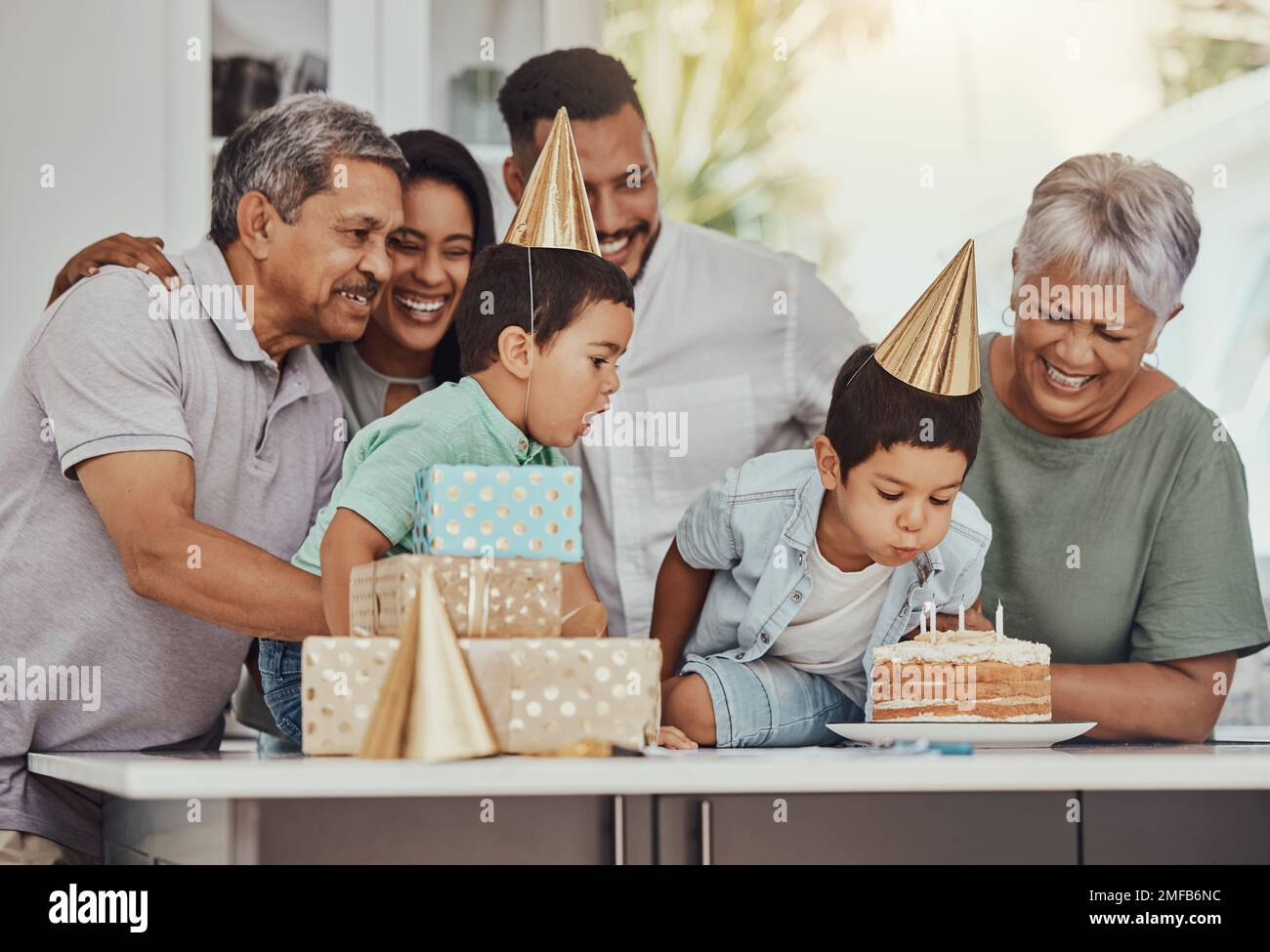 Geburtstag, Feier und Zwillingskinder mit Familie, die auf ihrer Party die Kerzen auf einen Kuchen bläst. Glücklich, aufgeregt und Kinder mit ihren Eltern und Stockfoto