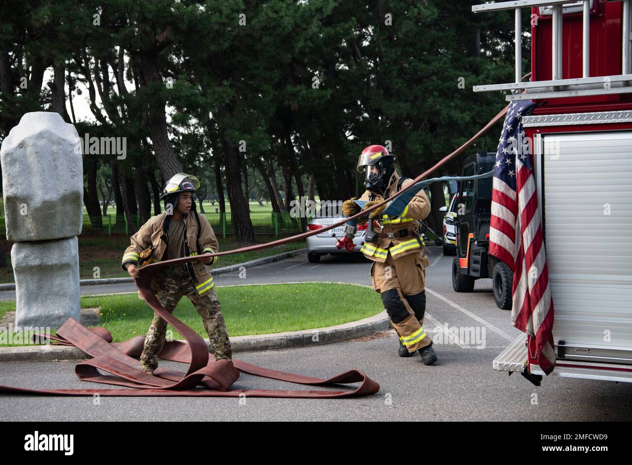 Senior Airman Marnier Dillard, Left, 8. Civil Engineer Squadron Fire Services Flight Driver Operator, und Staff Sgt. Colton Peer, 8. CES Fire Services Flight Crew Chief, zieht Feuerwehrschläuche während einer Schulung am Kunsan Air Base, Republik Korea, 19. August 2022. Während der Schulung übten die Feuerwehrleute das sichere Betreten des Gebäudes, die Rettung von Opfern und das Auffinden und Löschen der Flammen. Stockfoto
