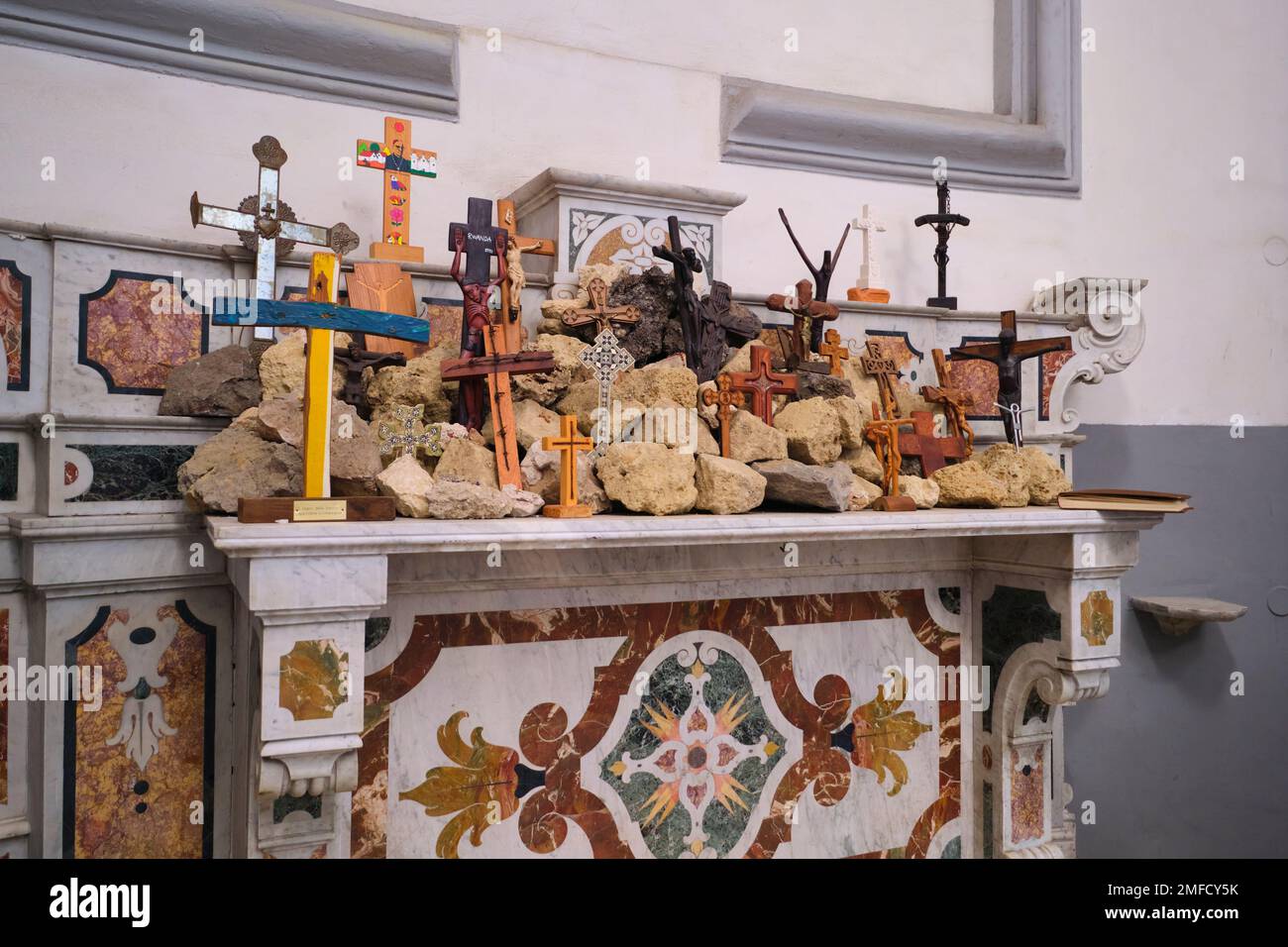Im Inneren der Kirche befindet sich ein kleiner, hausgemachter, provisorischer Schrein aus Felsen und Holzkreuzen auf einem Mantel. In der katholischen Kirche, Chiesa dei Santo Filippo e Gia Stockfoto