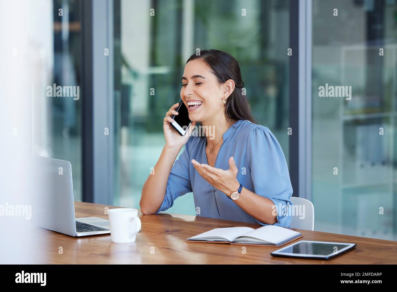 Telefonieren, kommunizieren und lachen mit einer Geschäftsfrau, die sich während der Arbeit in ihrem Büro unterhält. Laptop, Handy oder Internet mit einer Frau Stockfoto