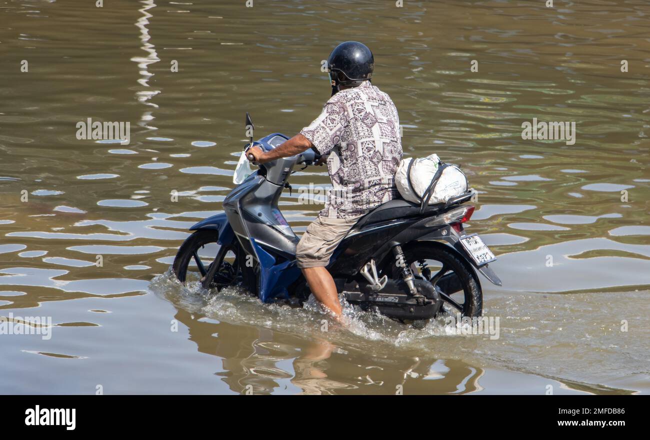 Ein Motorrad fährt auf einer überfluteten Straße, Thailand Stockfoto