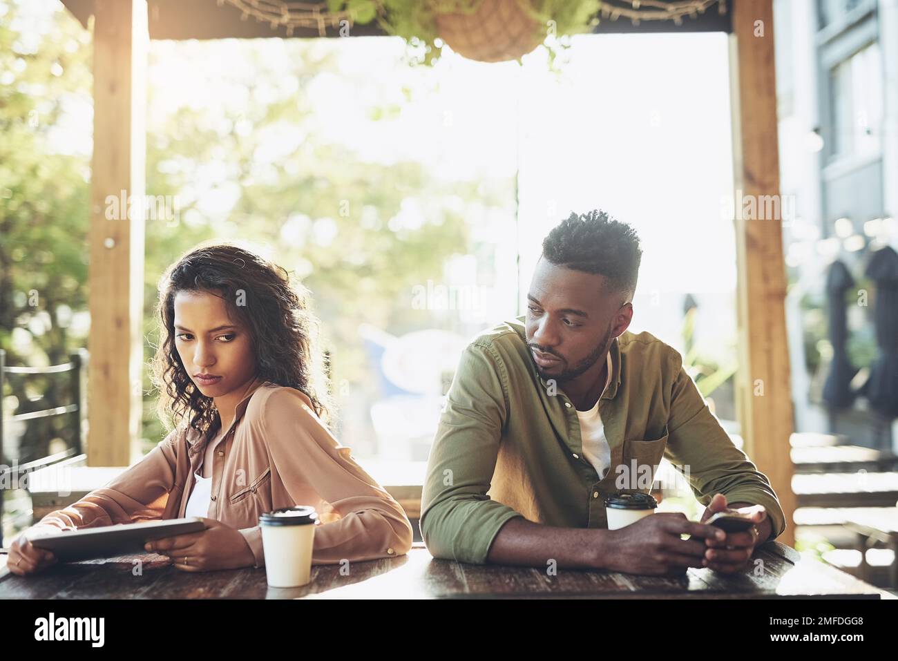 Soziale Medien können gut oder schlecht für Ihre Beziehung sein. Zwei junge Menschen, die ihre Wireless-Geräte in einem Café verwenden. Stockfoto