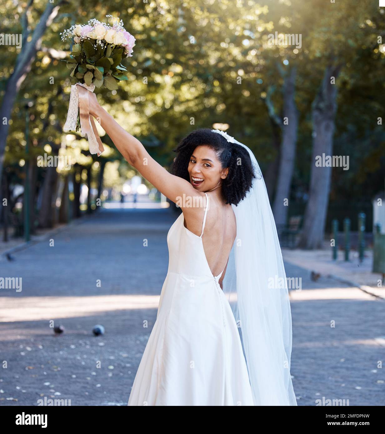 Braut, Hochzeit und schwarze Frau mit Blumen im Park draußen. Porträt, Heirat oder Schönheit einer glücklichen Frau, die einen Blumenstrauß von Rosen hochhält Stockfoto
