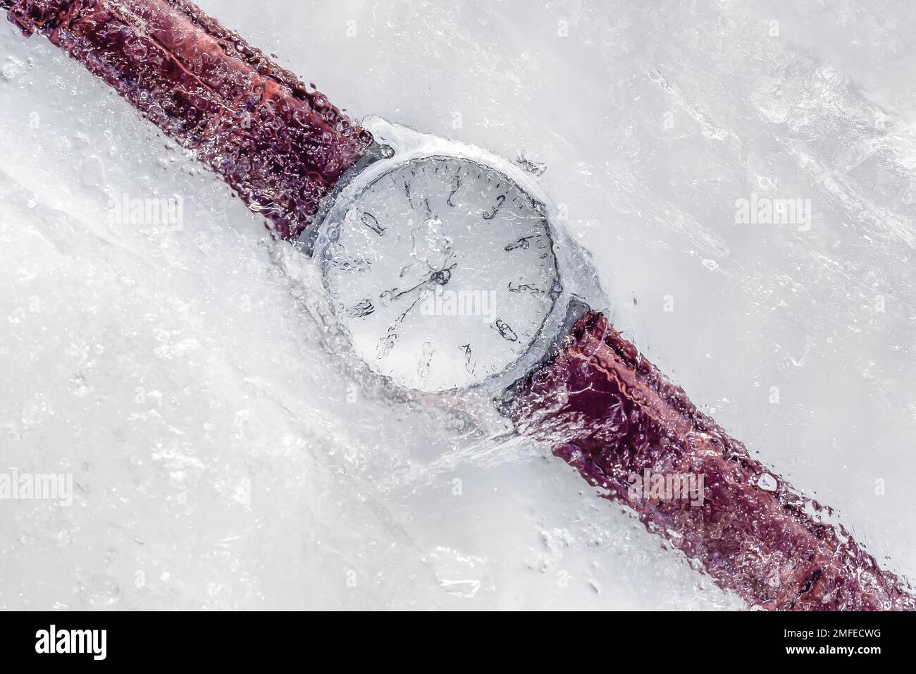 Unter Eis gefrorene analoge Uhr mit braunem Lederarmband. "Eingefroren in der Zeit" -Konzept Stockfoto
