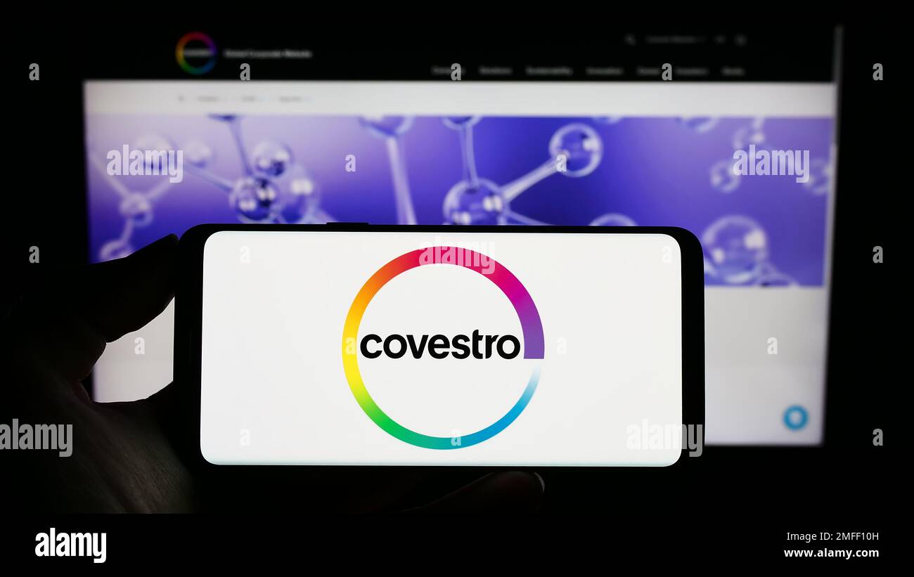 Person, die ein Mobiltelefon mit dem Logo des deutschen Chemieunternehmens Covestro AG auf dem Bildschirm vor der geschäftlichen Webseite hält. Konzentrieren Sie sich auf das Display des Telefons. Stockfoto