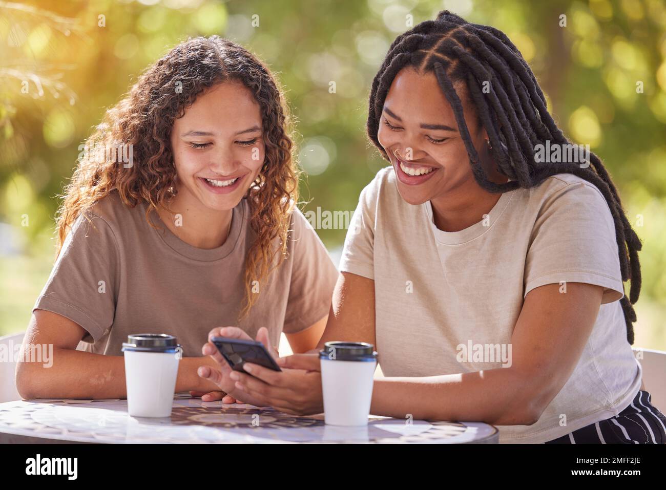 Smartphone, Universität und ein paar Freunde, die Benachrichtigungen, Beiträge in sozialen Medien oder lustige Meme im Campuscafé lesen. Park, Studenten oder Happy Black Stockfoto
