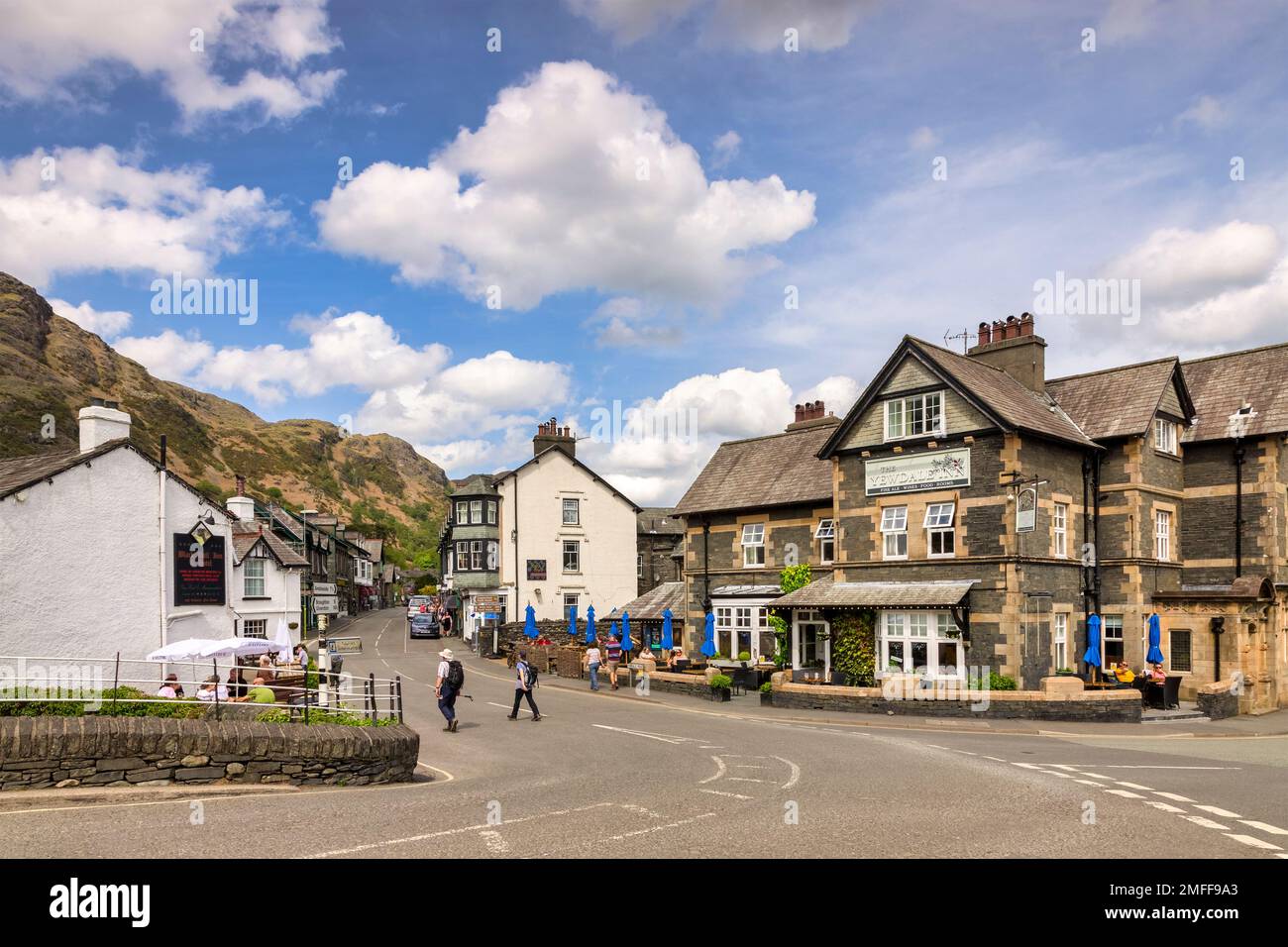 18. Mai 2022: Coniston, Cumbria, Großbritannien - das Zentrum von Coniston, ein beliebtes Dorf im English Lake District und das Yewdale Inn. Leute, die draußen sitzen... Stockfoto