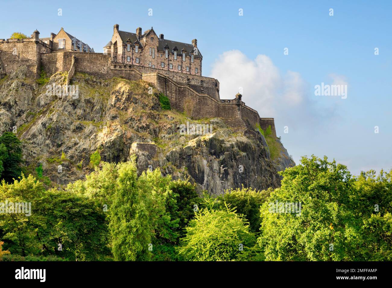 Edinburgh Castle, hoch oben auf dem Felsen über den Bäumen der Princes Street Gardens. Stockfoto