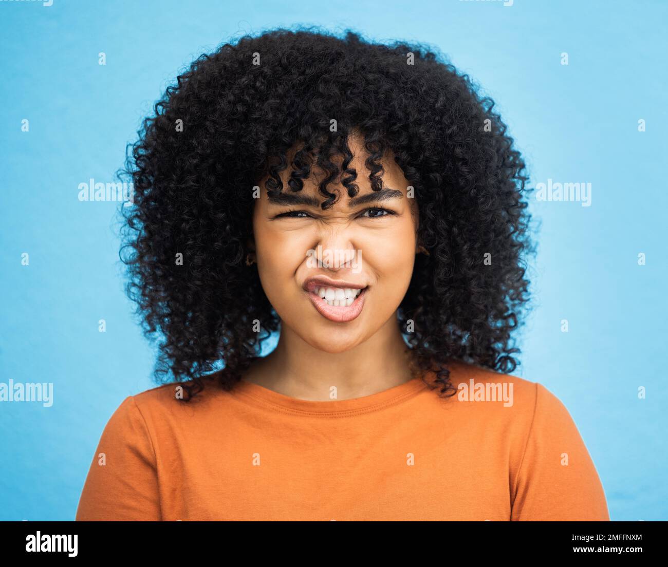 Porträt, Emoji und Frau mit Gesichtsausdruck im Studio für Spaß, Entspannung und verspielte Einstellung auf blauem Hintergrund. Gesicht, Comic und alberne schwarze Frau Stockfoto