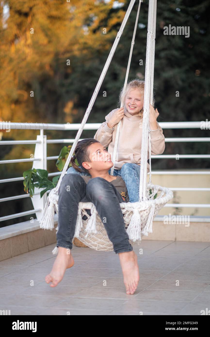 Erste Liebe, junge Freunde, Junge und Mädchen, die zusammen auf der Schaukel schwingen, Spaß haben, lachen. Stockfoto