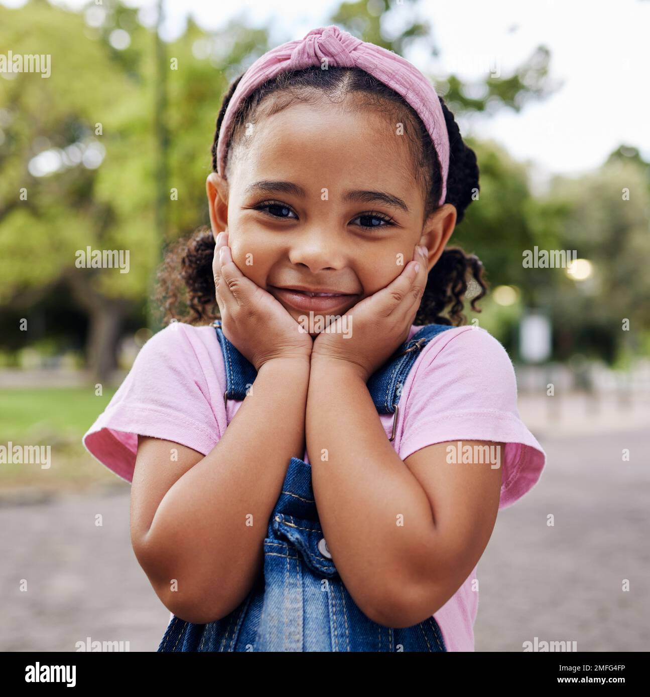 Süßes kleines Mädchen, Gesicht und Porträt lächeln in bezauberndem pinkfarbenem Freizeitlook mit Jeans im Outdoor-Park. Glückliches Mädchen, das glücklich lächelt Stockfoto