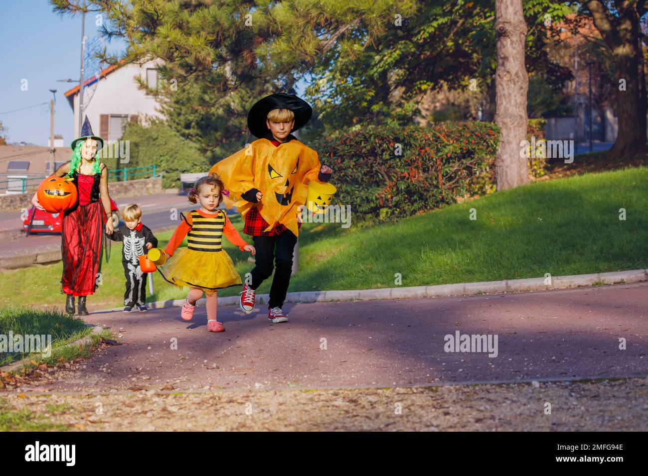 Familien mit Kindern gehen in Halloween-Kostümen, Eimer halten Stockfoto