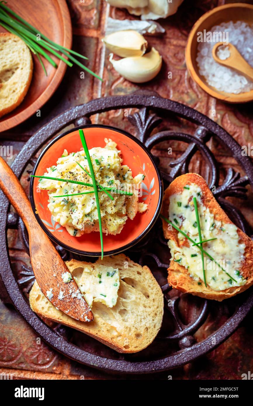 Hausgemachtes Knoblauchbrot oder Baguettscheiben mit Knoblauchbutter und Kräutern auf dem Küchentisch Stockfoto