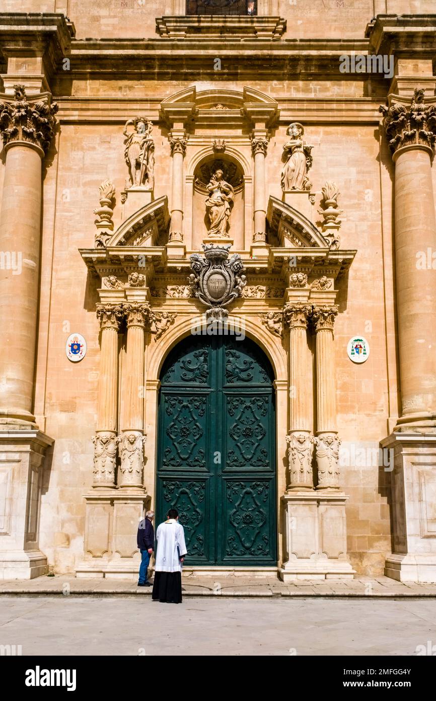 Ein Priester nähert sich dem westlichen Eingang der Kirche Ragusa Kathedrale, Duomo di Ragusa, Cattedrale di San Giovanni Battista. Stockfoto