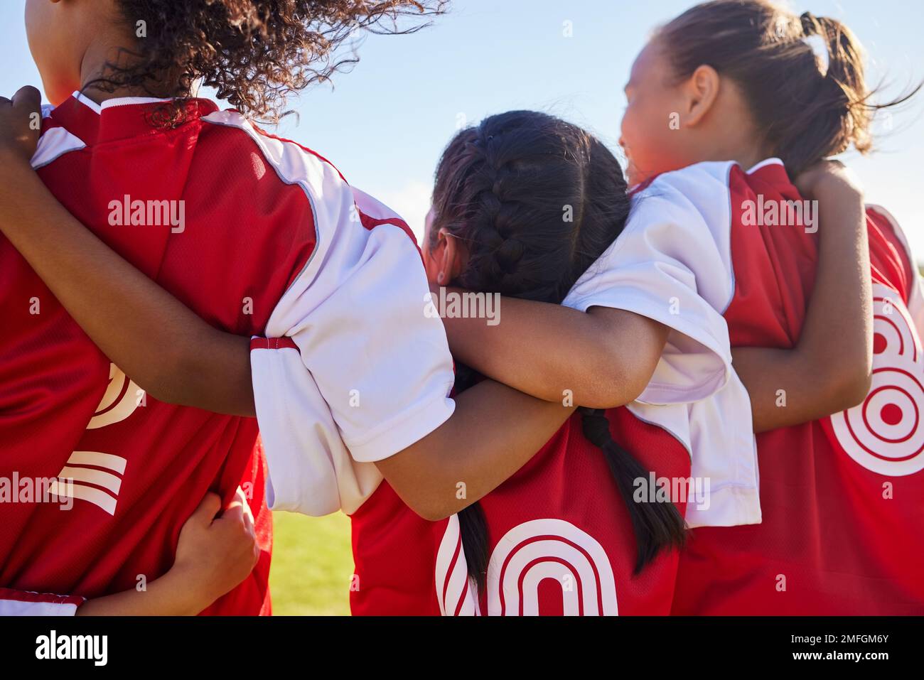 Mädchen, Fußballgruppe und zurück mit Teambuilding-Unterstützung auf dem Spielfeld für Spiel, Wettkampf oder Spiel. Weibliche Kinder, Fußballspielerkinder und Umarmung Stockfoto