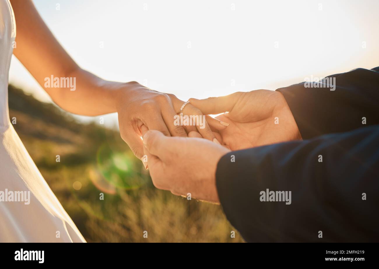 Ein Paar Hände, ein Ehering und ein Treuhandverhältnis, Hoffnung und Liebe zusammen in der Natur im Freien. Braut, Bräutigam, Termin, Unterstützung und Schmuck Stockfoto