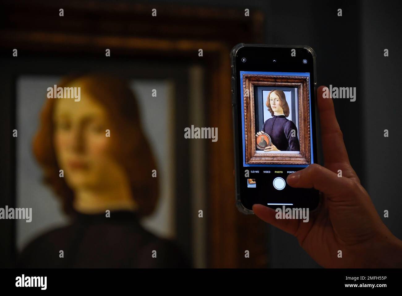 A member of the staff takes a phone picture of the painting 'Young Man Holding a Roundel' by the Italian Renaissance painter Sandro Botticelli at Sotheby's, in London, Wednesday, Dec. 2, 2020. The painting will be presented during the Sotheby's Masters Week Auctions in January 2021 in New York, US, and it is estimated to sell for in excess of $80 million. (AP Photo/Alberto Pezzali) Stockfoto