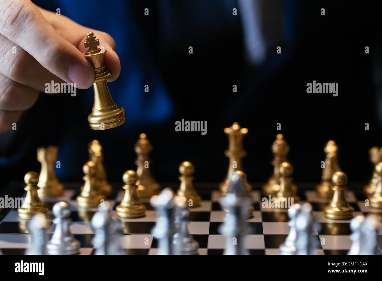 Nicht erkennbare Mann in Anzug und goldene König beim Schach spielen gegen grauer Hintergrund Stockfoto
