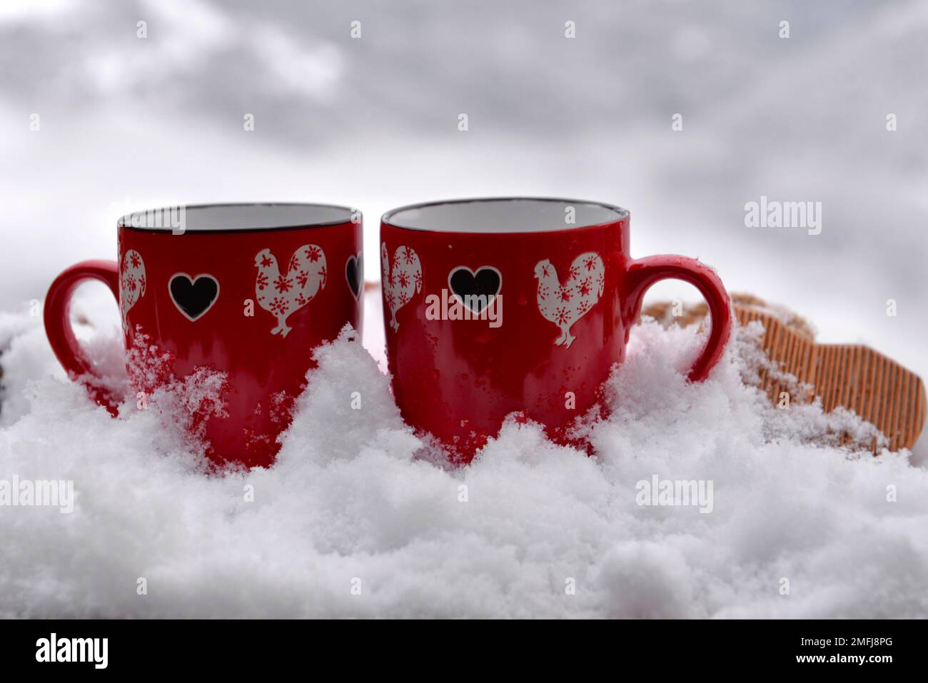 Zwei rote Tassen mit Herzform auf dem schneebedeckten valentinskonzept Stockfoto