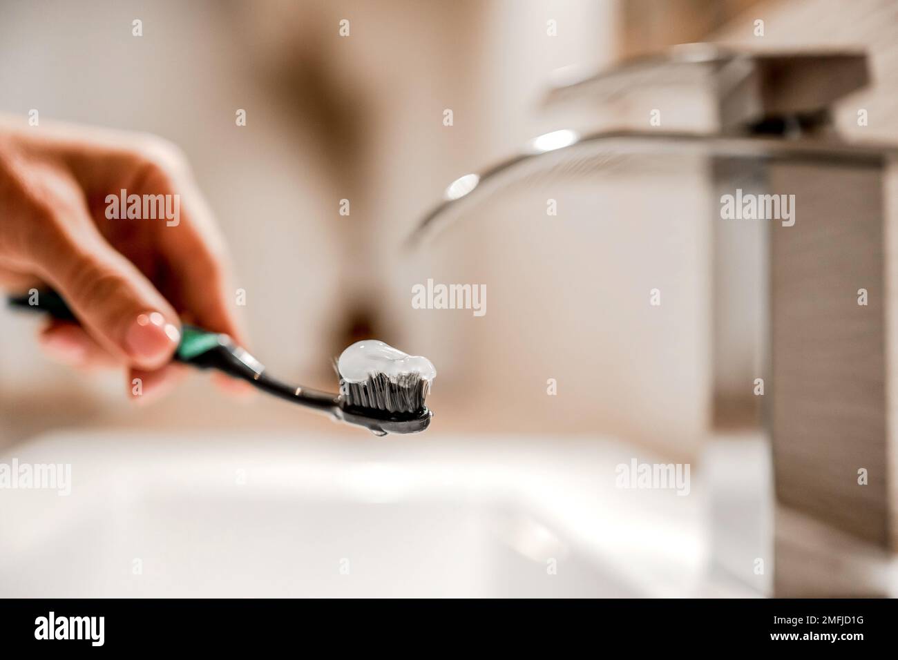 Mädchenhand hält Zahnbürste mit Paste unter fließendem Wasser Stockfoto