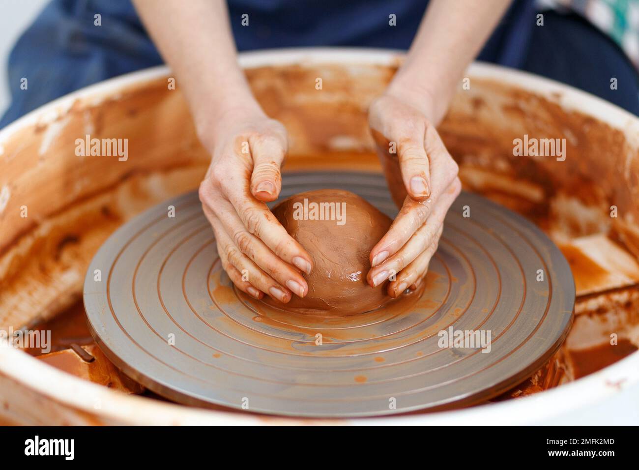 Zugeschnittenes Bild eines nicht wiedererkennbaren weiblichen Keramikherstellers, der mit Ton auf Töpferrad in Cozy Workshop, Creative People Handcraft Pottery Class arbeitet. Stockfoto