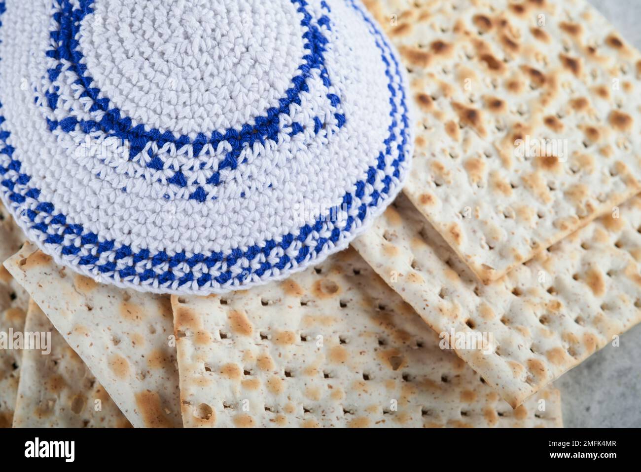 Das Konzept der Pessachstunde. Matzah, roter Koscher und Walnuss. Traditionelles jüdisches Brot Matzah, Kippah und Tallit auf altem Betonhintergrund. Pas Stockfoto