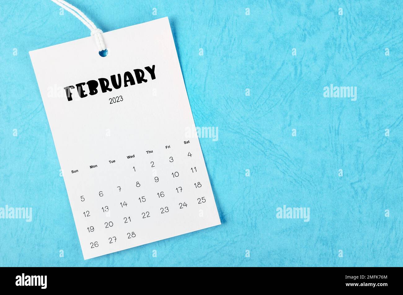 Kalenderseite für den 2023. Februar hängt auf weißem Seil auf blauem Hintergrund. Stockfoto