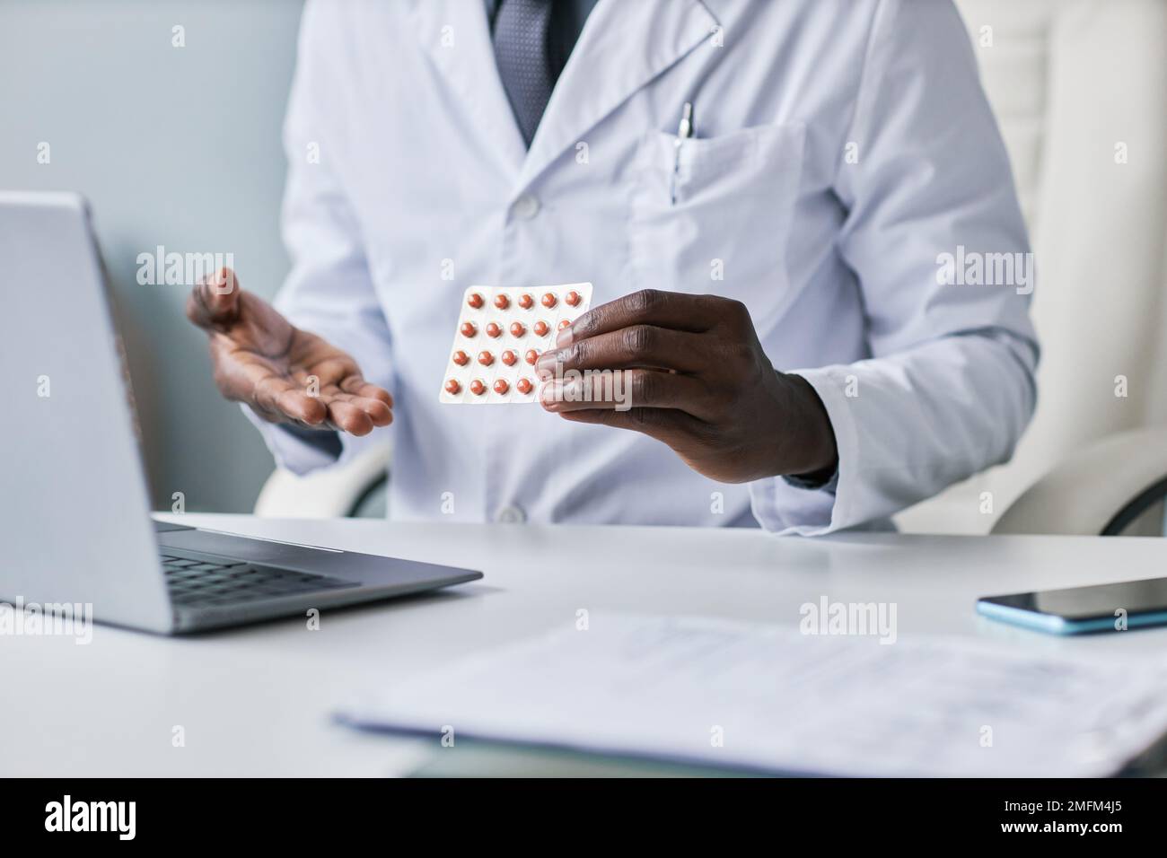 Nahaufnahme eines schwarzen Arztes, der Tabletten hält und dem Kunden bei der Online-Beratung Medikamente erklärt Stockfoto